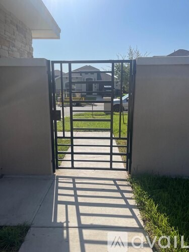 A black gate is open to a driveway.