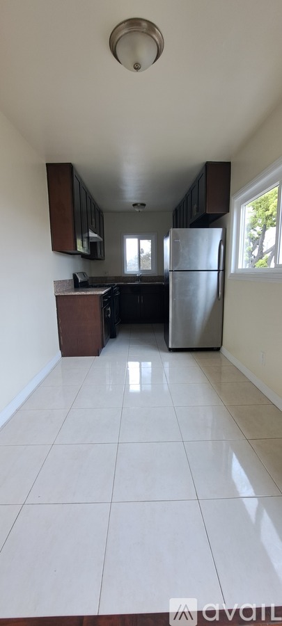 A kitchen with white tiled floors and a refrigerator.