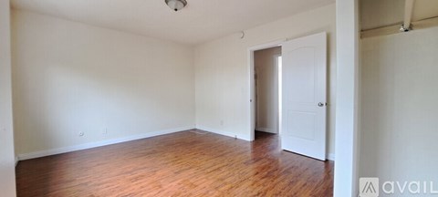 A room with wooden floors and white walls is available for rent.