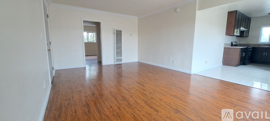 A spacious room with wooden flooring and white walls.