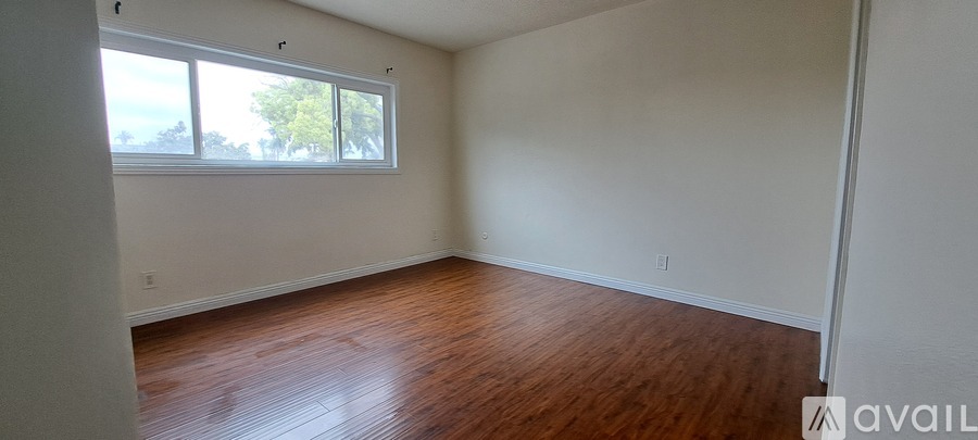 A room with wooden floors and white walls is available for rent.