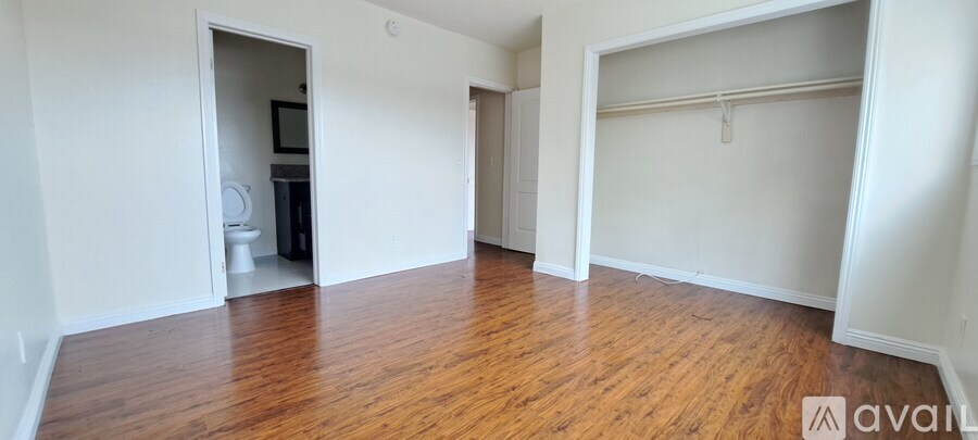 A room with wooden floors and white walls, with a doorway leading to another room.