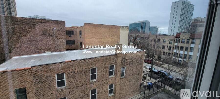 A view of a cityscape from a window with a building in the foreground and a street below.