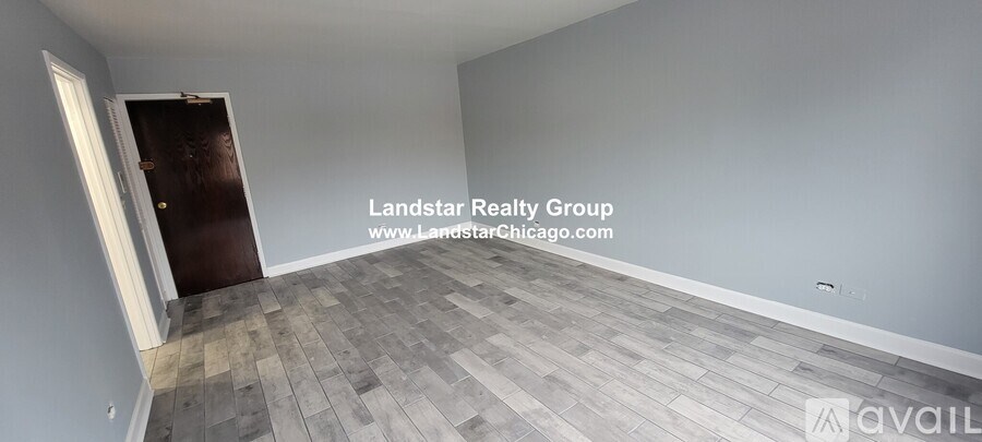 A room with a wooden floor and a door on the left side.