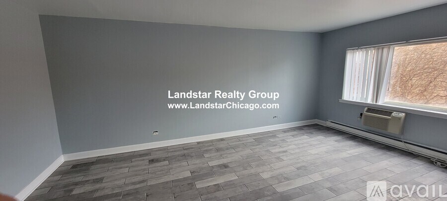 A room with a window and a wall that has a Landstar Realty Group logo on it.