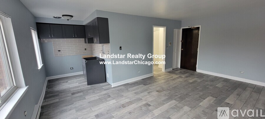A room with grey flooring and a window on the left side.