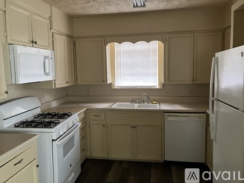 A kitchen with white appliances and wooden cabinets.
