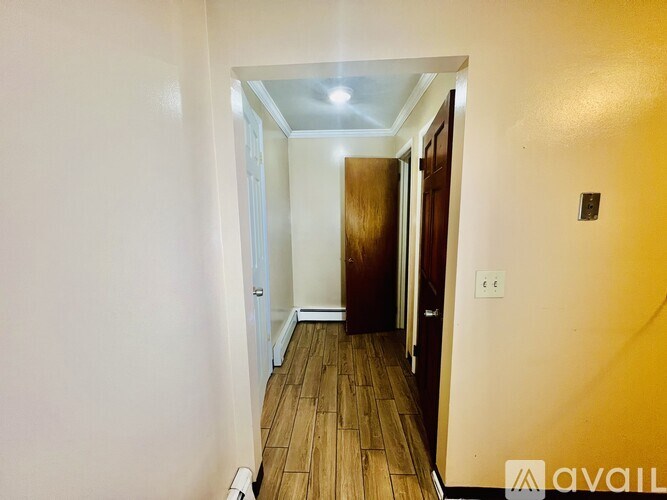 A hallway with a wooden floor and white walls.