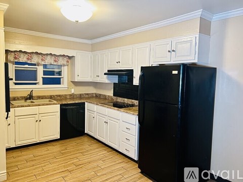 A kitchen with black appliances and white cabinets.