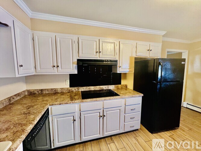 A kitchen with black appliances and white cabinets.