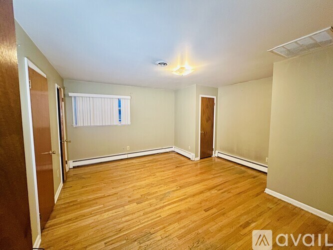 A room with wooden flooring and a window with blinds.