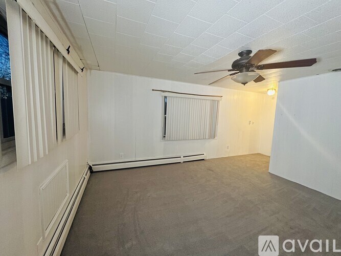 A room with a ceiling fan and a window with blinds.