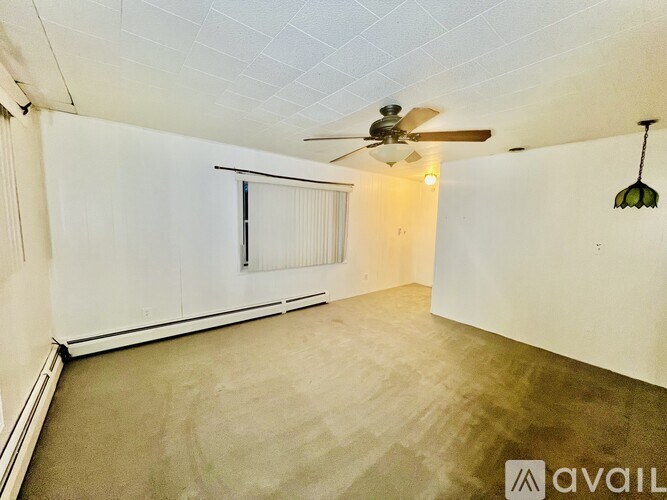 A room with a ceiling fan and a window with blinds.
