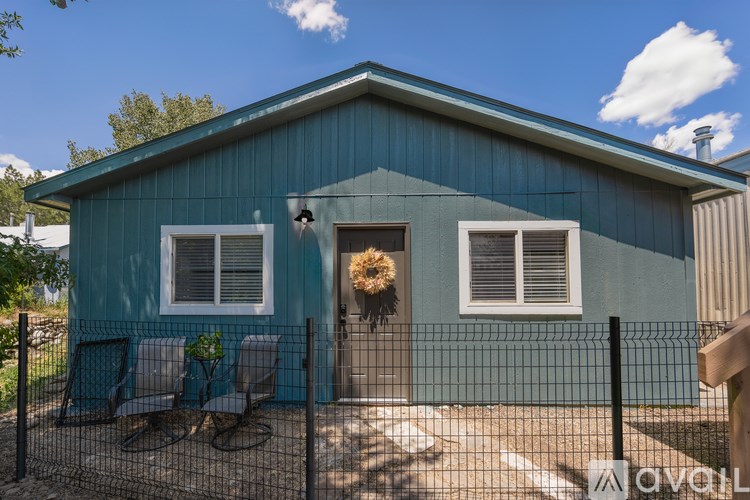 A blue house with a fence and a hanging plant in front.