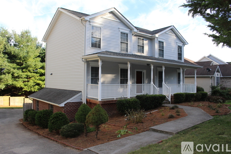 A two-story house with a front porch and a driveway.