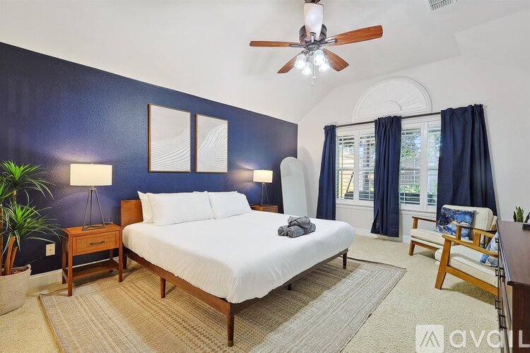 A bedroom with a bed, nightstand, and a ceiling fan.