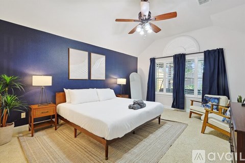 A bedroom with a bed, nightstand, and a ceiling fan.