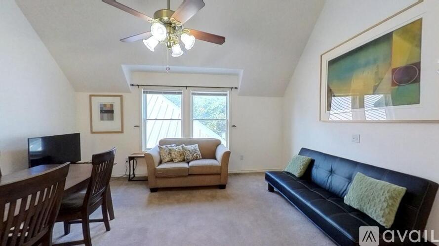 A living room with a black couch, a television, and a painting on the wall.
