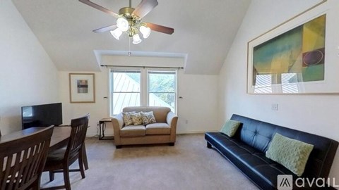 A living room with a black couch, a television, and a painting on the wall.