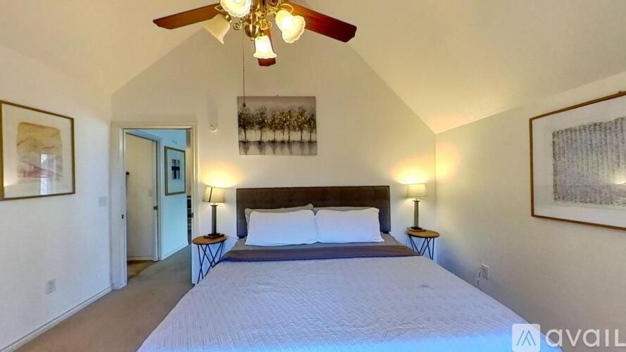 A bedroom with a large bed and a ceiling fan.