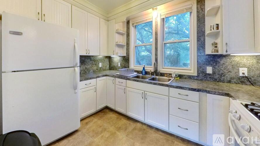 A kitchen with white cabinets and a black chair.