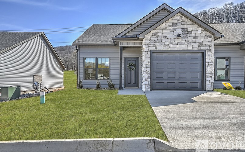 A house with a grey garage door and a stone facade.