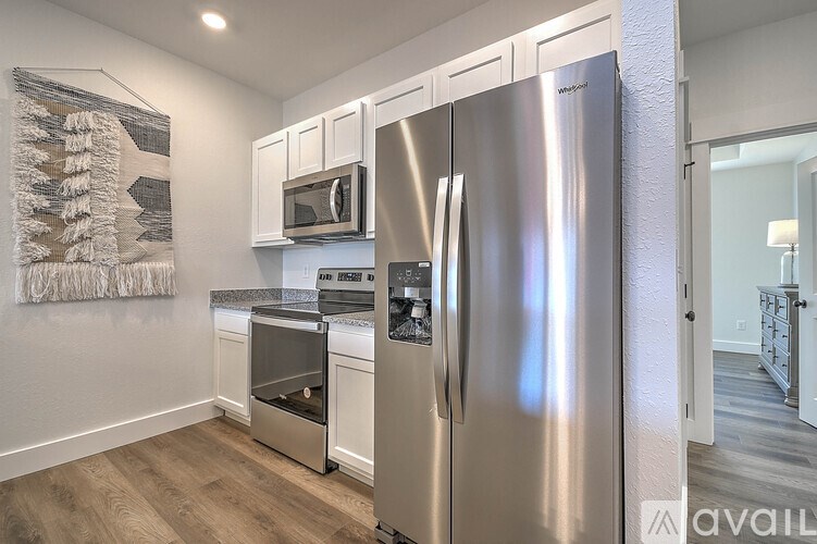 A modern kitchen with a stainless steel refrigerator and white cabinets.