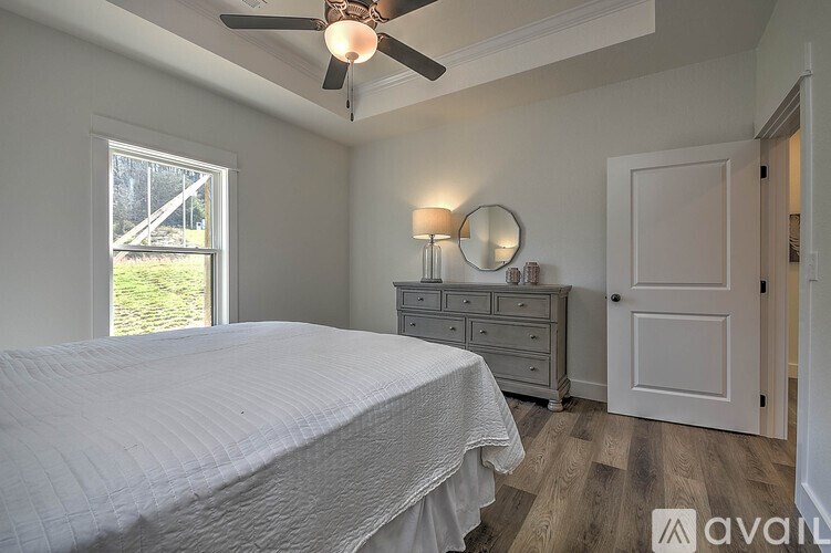 A bedroom with a bed, dresser, and window.