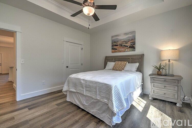 A bedroom with a bed, nightstand, and a painting on the wall.