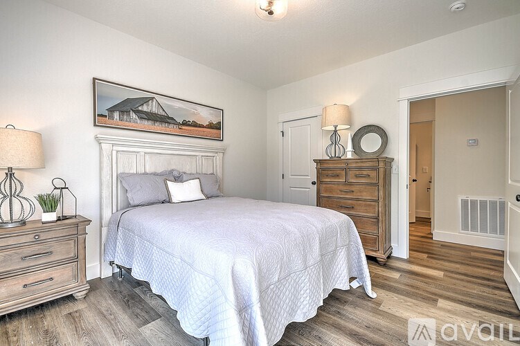 A bedroom with a bed, dresser, and a painting on the wall.