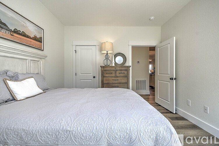 A bedroom with a large bed and a painting on the wall.
