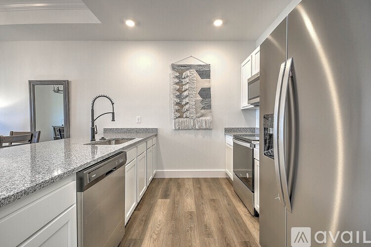 A modern kitchen with stainless steel appliances and wooden flooring.
