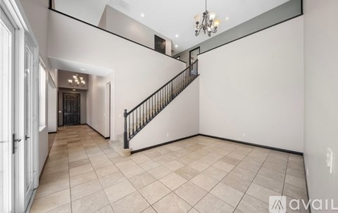 A spacious room with a staircase and a chandelier.