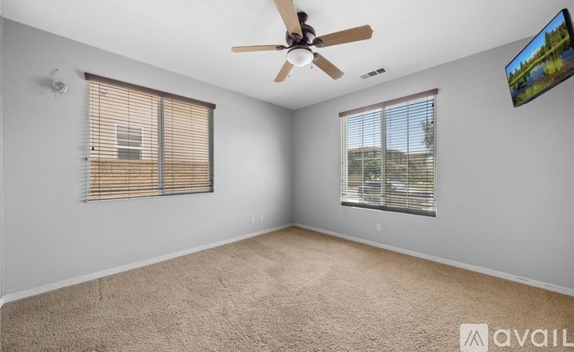 A room with a ceiling fan and a window with blinds.