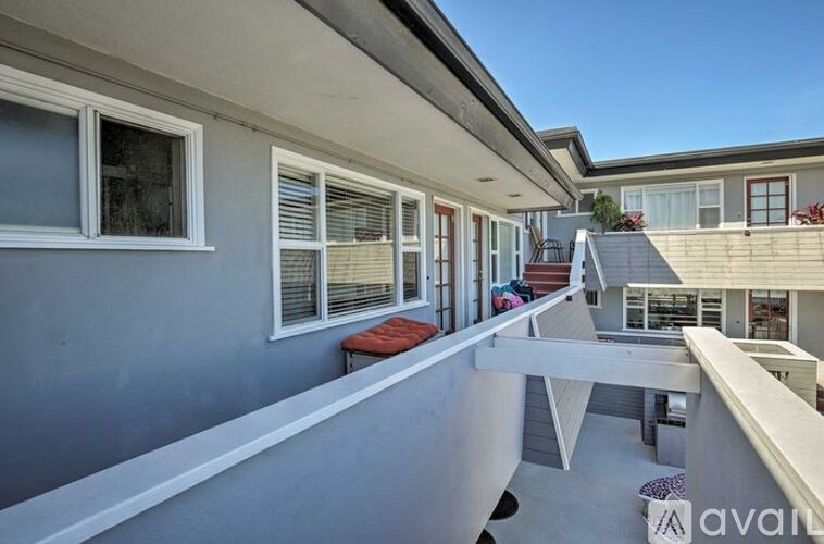 A balcony with a bench and a table is on the second floor of a house.