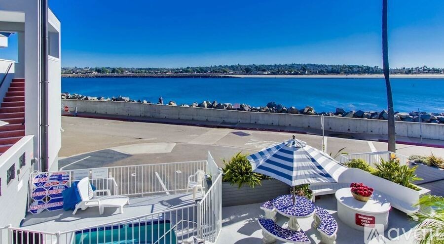 A balcony with a table and chairs overlooking a body of water.