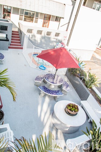 A red umbrella is on a table with a bowl of fruit on it.