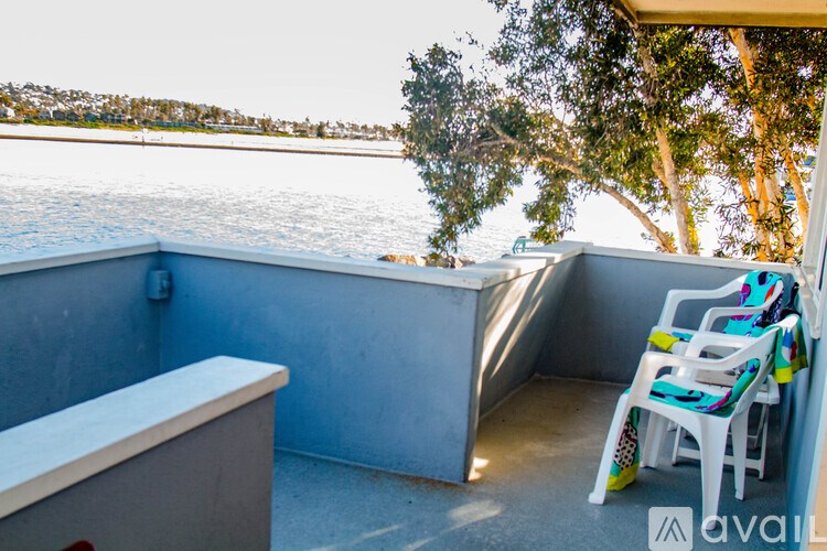 A balcony with chairs and a table overlooking a body of water.