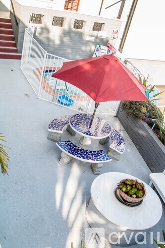 A red umbrella is on a table with a bowl of fruit on it.