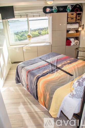 A bedroom with a bed covered in blankets and a window overlooking a green landscape.