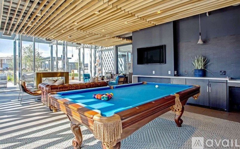 A pool table in a room with a wooden ceiling and a television mounted on the wall.