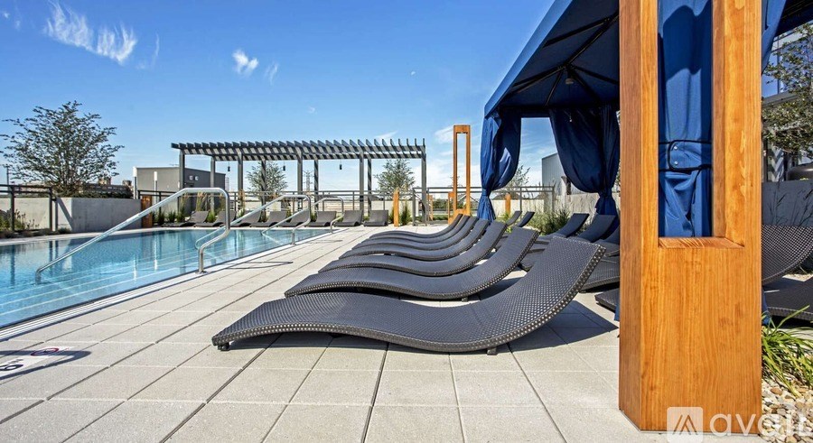A pool with sun loungers and a blue sky.