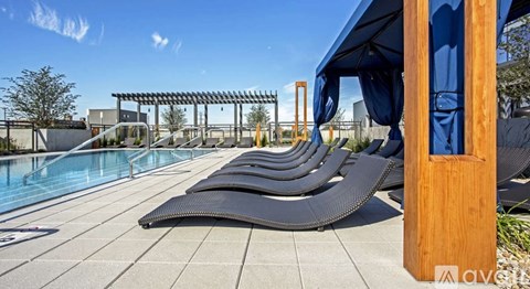 A pool with sun loungers and a blue sky.