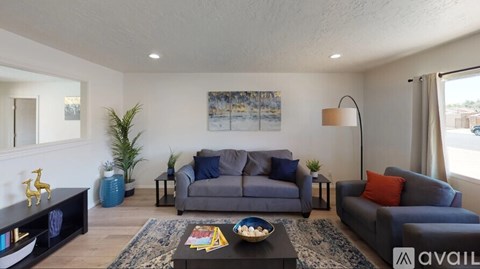 A living room with a grey couch and a blue vase.