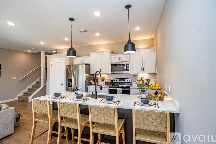 A kitchen with a table set for two and a staircase in the background.