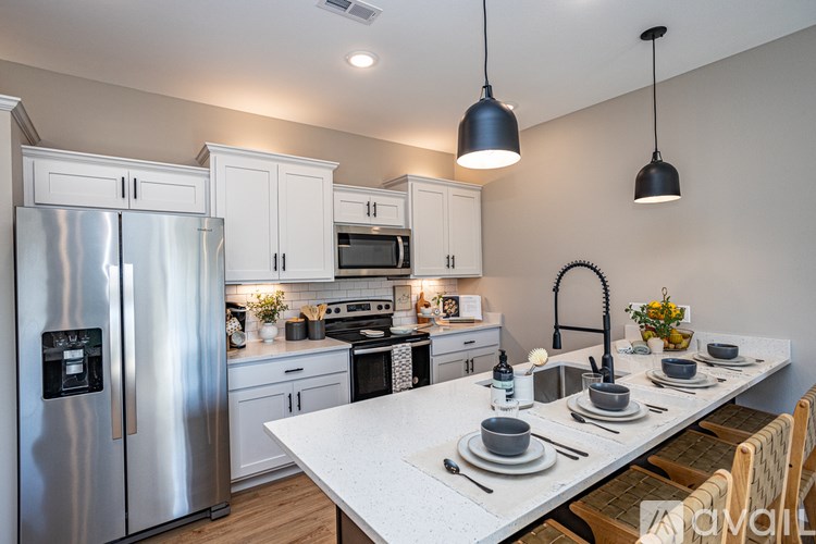 A kitchen with a refrigerator, microwave, oven, sink, and dining table.