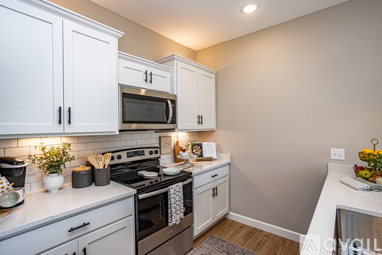 A kitchen with white cabinets and a black microwave.