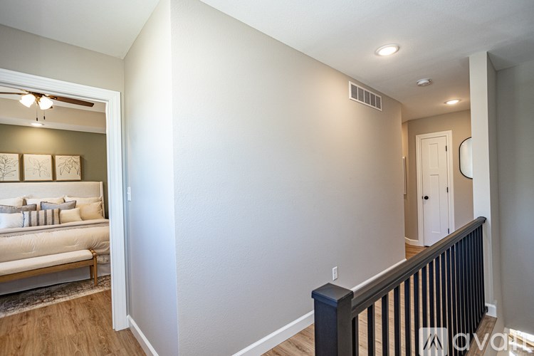A well-lit, empty room with a sofa and a bed in the background.
