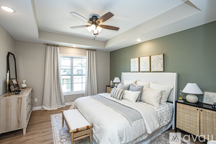 A bedroom with a large bed, a ceiling fan, and a window with curtains.