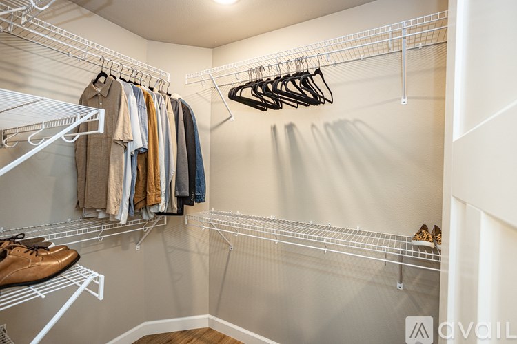 A walk in closet with clothes and shoes on shelves.